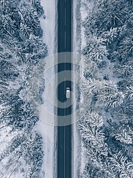 Country road going through the beautiful snow covered landscapes. Aerial view.