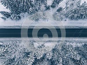 Country road going through the beautiful snow covered landscapes. Aerial view.