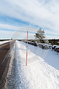 Country road with a red snow stake by roadside