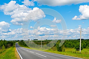 Country road. Summer sunny day. White clouds in the blue sky.