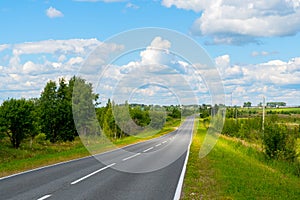 Country road. Summer sunny day. White clouds in the blue sky.