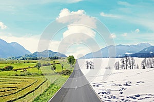 Country road through winter and spring landscape