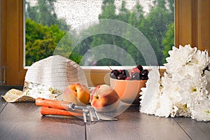 Country still life. The harvest from the garden - cherries, peaches. Chrysanthemum flowers, garden tools and summer hat on the