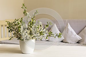 Country style living room. Cherry flower in white pot on wooden table. Still life