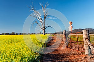 Country woman basking in the spring sunshine looking out over the fields of canola