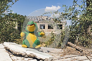 Countryside. A child\'s soft toy in front of a house destroyed by artillery shelling