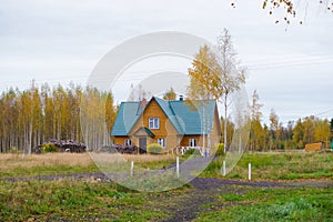 Countryside cottage with pile of logs in autumn day