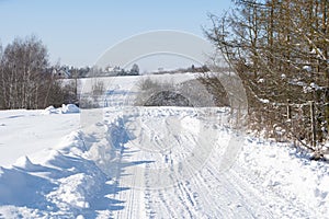 Countryside dirt road full of snow in winter. You can see the traces of cars and the road after snow removal.