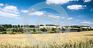 countryside with fields, pond, meadows, small hills and blue sky with clouds near Zdar nad Satavou city in Czech republic