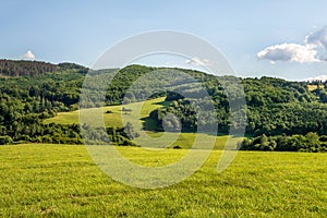 Countryside at high noon. Rural scenery with trees and fields on the rolling hills at the foot of the ridge