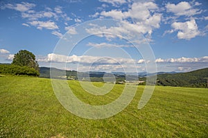 Countryside at high noon. Rural scenery with trees and fields on the rolling hills at the foot of the ridge