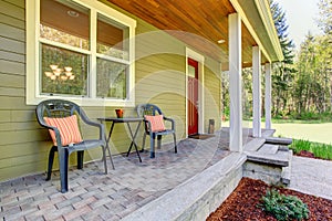 Countryside house exterior. View of entrance porch with chairs
