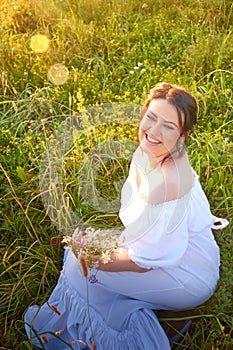 Countryside plump chubby pleasant woman in white dres in green grass field. Girl in an old Russian dress of a noblewoman