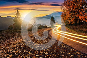 Countryside road with car lights at sunset