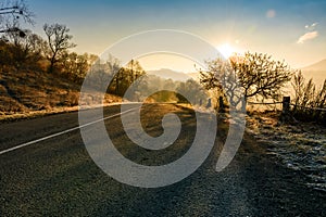 Countryside road in late autumn fog at sunrise