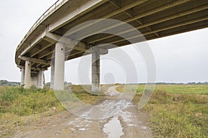 Countryside road passing under a highway bridge