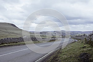 Countryside road with stone walls aside in Peak District National Park,Derbyshire,Uk.Cloudy sky and scenic panorama in background