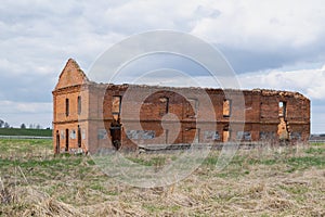 countryside rural landscape. an old, ruined, abandoned red brick building stands on the field.