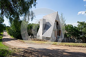 Countryside shot of triangular frame house, A-shaped hut near rural road on sunny day