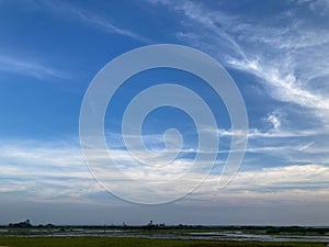 Countryside view of green fields and river with wide clear bright blue sky