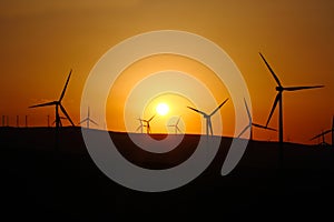 countryside with wind turbines and the setting sun