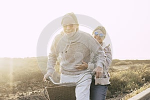 Couple of active cheerful and happy senior retired people enjoy together riding a bike in outdoor leisure activity with sun in