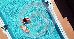 Couple of active senior people enjoy the vacation or retired lifestyle on a blue swimming pool with funny lilos