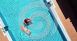 Couple of active senior people enjoy the vacation or retired lifestyle on a blue swimming pool with funny lilos - happiness and re