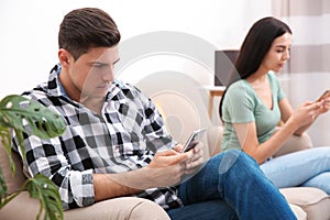 Couple addicted to smartphones ignoring each other at home