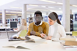 Couple of adult students studying together in public library