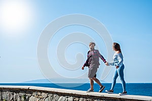 Couple of adults walking together taking their hands with the ocean or sea and beautiful island background - happy vacations