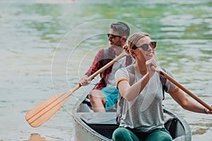 Couple adventurous explorer friends are canoeing in a wild river surrounded by the beautiful nature