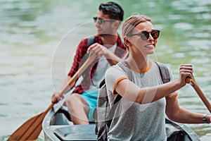 Couple adventurous explorer friends are canoeing in a wild river surrounded by the beautiful nature