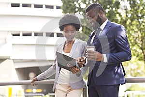 Couple of african american business partners working while standing outdoors