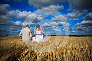 Couple against blue sky among rye fertility simbol photo