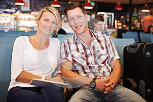 Couple In Airport Departure Lounge Waiting To Go On Vacation