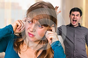 Couple arguing, angry man screaming at his wife at home