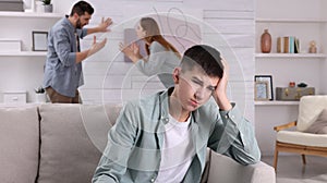 Couple arguing at home, focus on their unhappy teenage boy. Problems in family