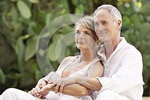 Couple With Arms Around Relaxing In Garden