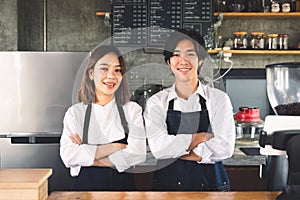 Couple asian barista owner coffee shop standing at counter welcome the customer. Cheerful two young barista man and woman in apron