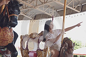 Couple asian man and woman dating and riding on horse at Carousel amusement park. Concept happy and lovely life of teenager