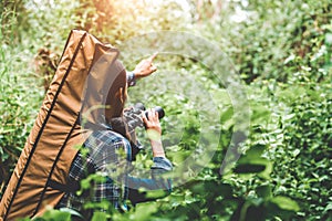 Couple of Asian people holding binoculars telescope in forest looking forward to destination. People lifestyles and leisure