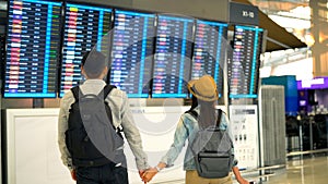 Couple Asian people walking in airport terminal waiting for  flight boarding.