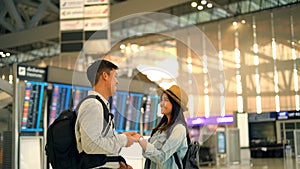 Couple Asian people walking in airport terminal waiting for  flight boarding.