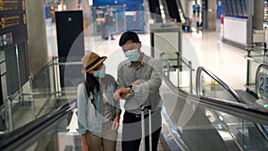 Couple Asian people walking in airport terminal waiting for  flight boarding.