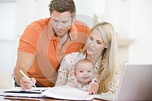 Couple and baby in dining room with laptop