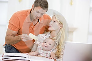 Couple and baby with laptop and paper