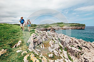 Couple backpacker travelers walk on ocean rocky coast