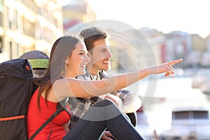 Couple of backpackers pointing landmark in the street photo