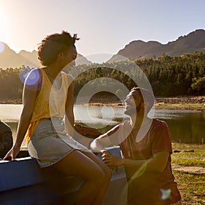 Couple With Backpacks In Pick Up Truck On Road Trip By Lake At Sunset